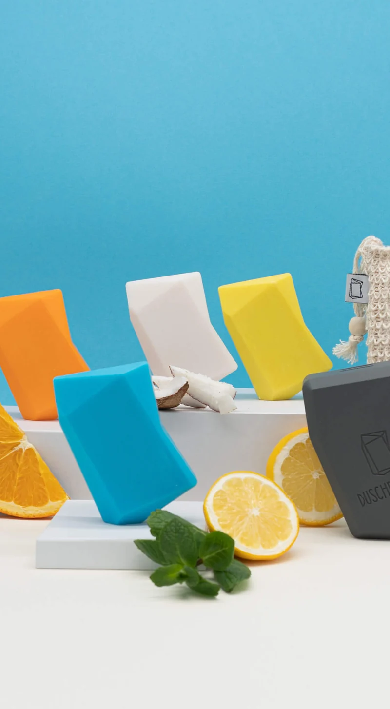 Colourful Duschbrocken bars with citrus fruit against a blue wall